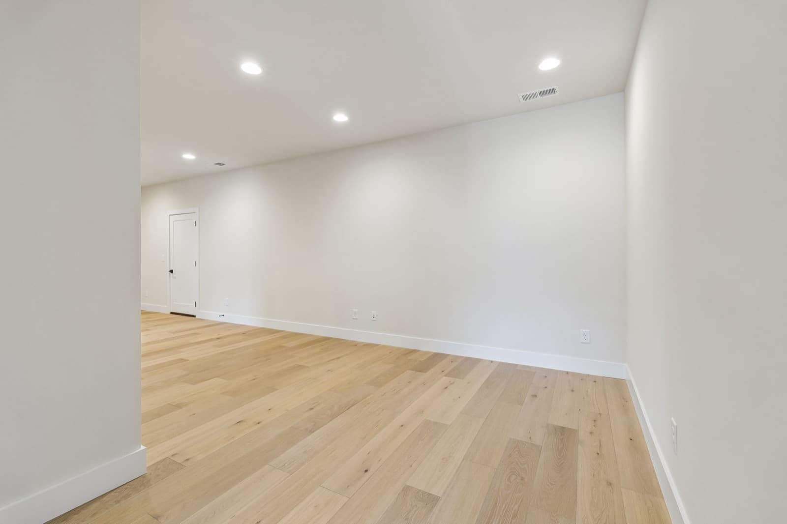Upstairs loft at 123 Shadow Springs, a long open room with hardwood floors and a door at the far end.