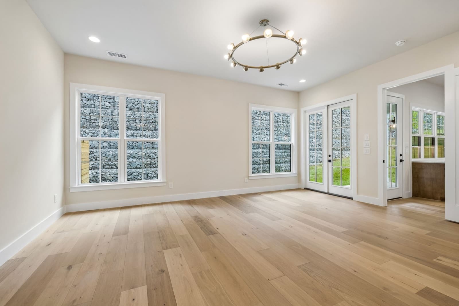 Main-level primary bedroom at 125 Shadow Springs with two windows and French doors looking onto the stacked-stone wall.