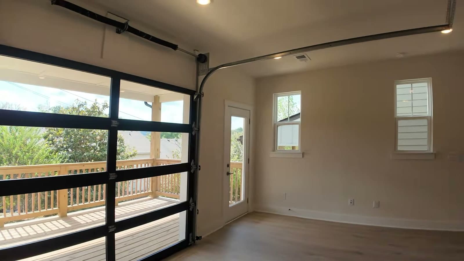 The glass garage-style door at 2008 Sonya Terrace raised on its tracks, with the covered wood deck, railing and trees beyond, a separate glass door to the deck, and two more windows on the right-hand wall.